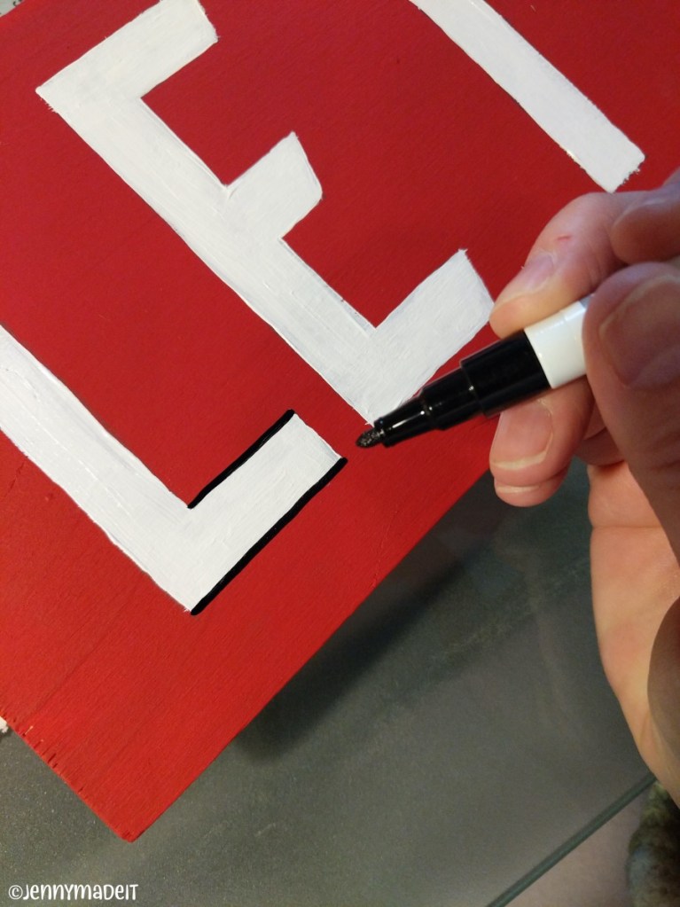 Photo of me using a black paint pen to outline each painted letter.