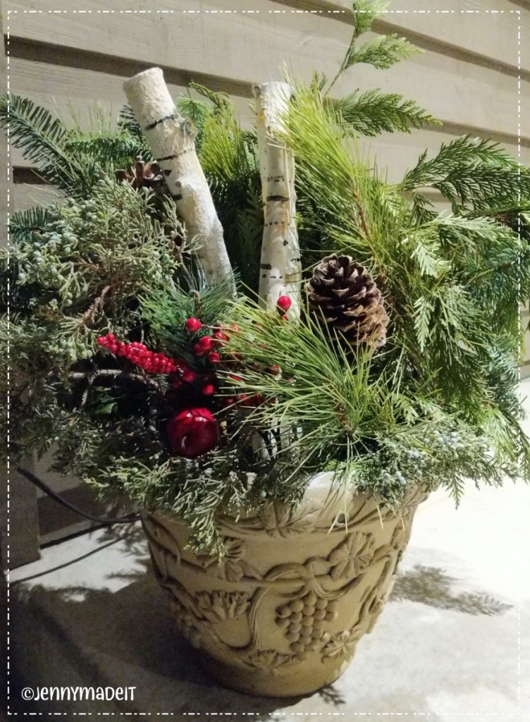 Photo of a Christmas planter with greenery, pine cones, red berries and my painted birch logs.